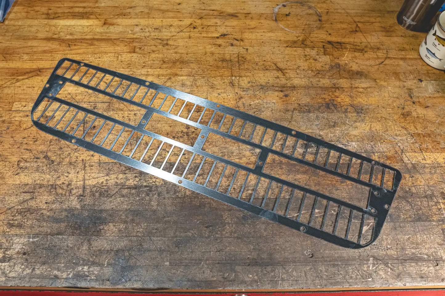 Metal grate placed on a wooden workbench.