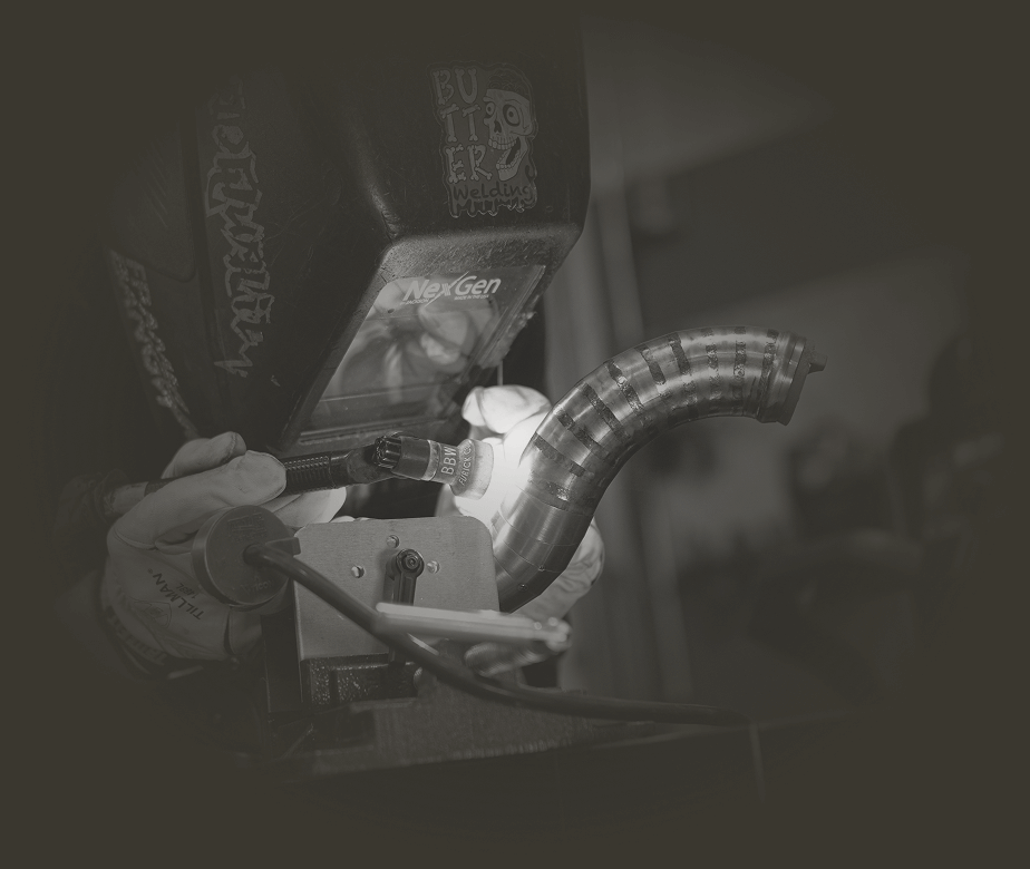 Person welding a metal pipe with a protective mask.